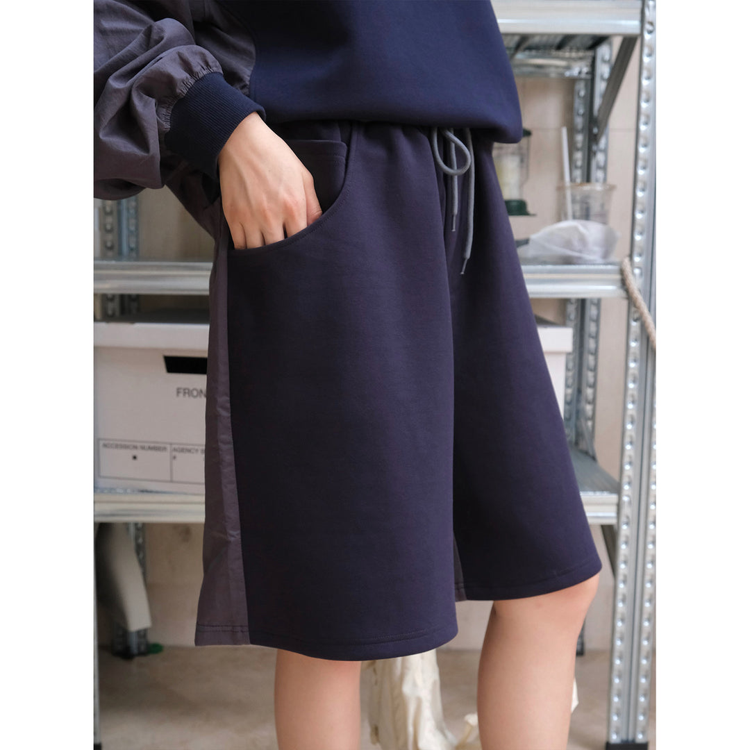Women's knee-length sweat shorts with elastic waistband, drawstring, and side satin detail
