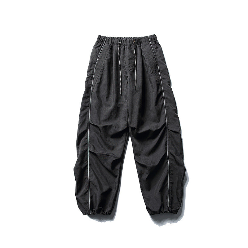 [Men] loose-fitting nylon jogger pants in utility style with drawstring waistband, contrast piping, and elastic ankle cuffs Amarae