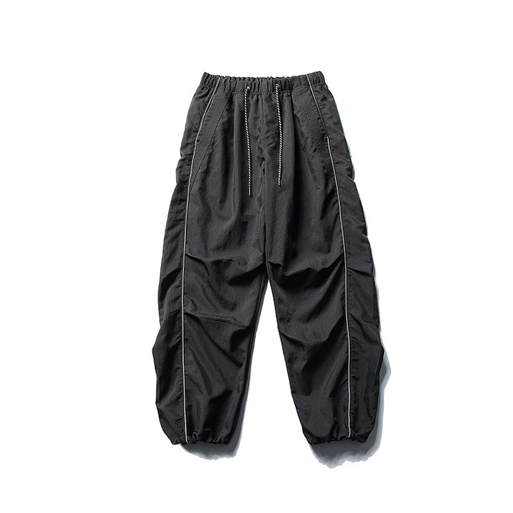 [Men] loose-fitting nylon jogger pants in utility style with drawstring waistband, contrast piping, and elastic ankle cuffs Amarae