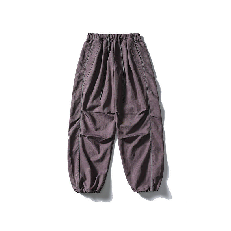 [Men] loose-fitting nylon jogger pants in utility style with drawstring waistband, contrast piping, and elastic ankle cuffs Amarae