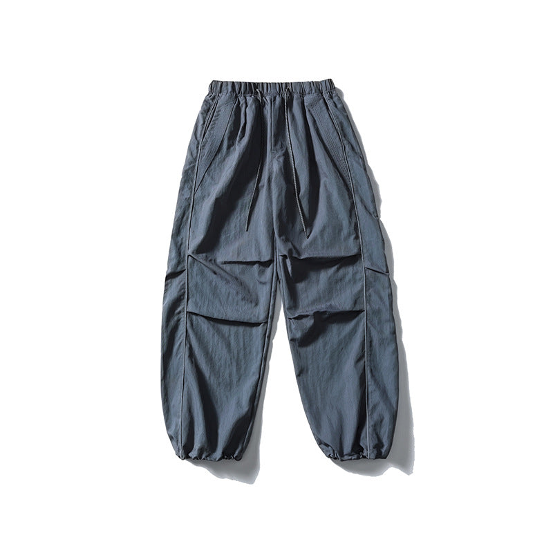 [Men] loose-fitting nylon jogger pants in utility style with drawstring waistband, contrast piping, and elastic ankle cuffs Amarae