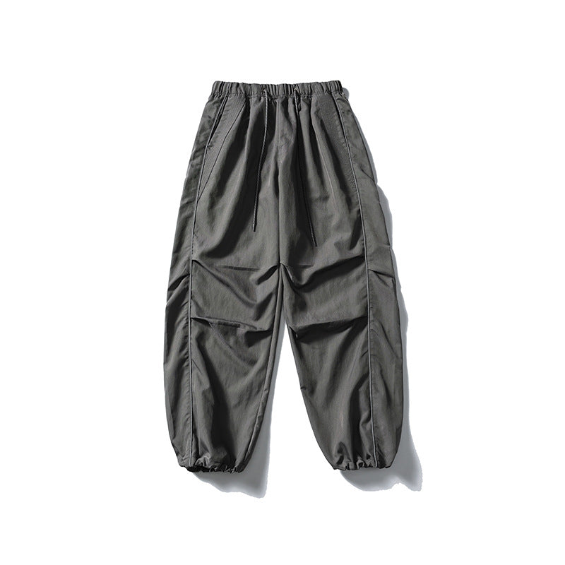 [Men] loose-fitting nylon jogger pants in utility style with drawstring waistband, contrast piping, and elastic ankle cuffs Amarae