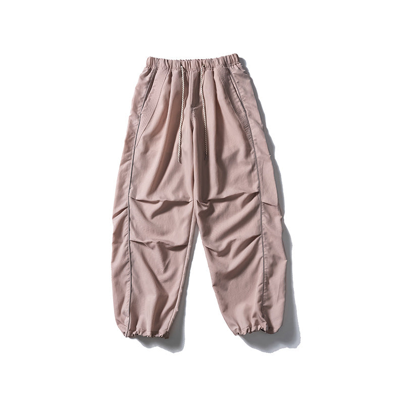 [Men] loose-fitting nylon jogger pants in utility style with drawstring waistband, contrast piping, and elastic ankle cuffs Amarae